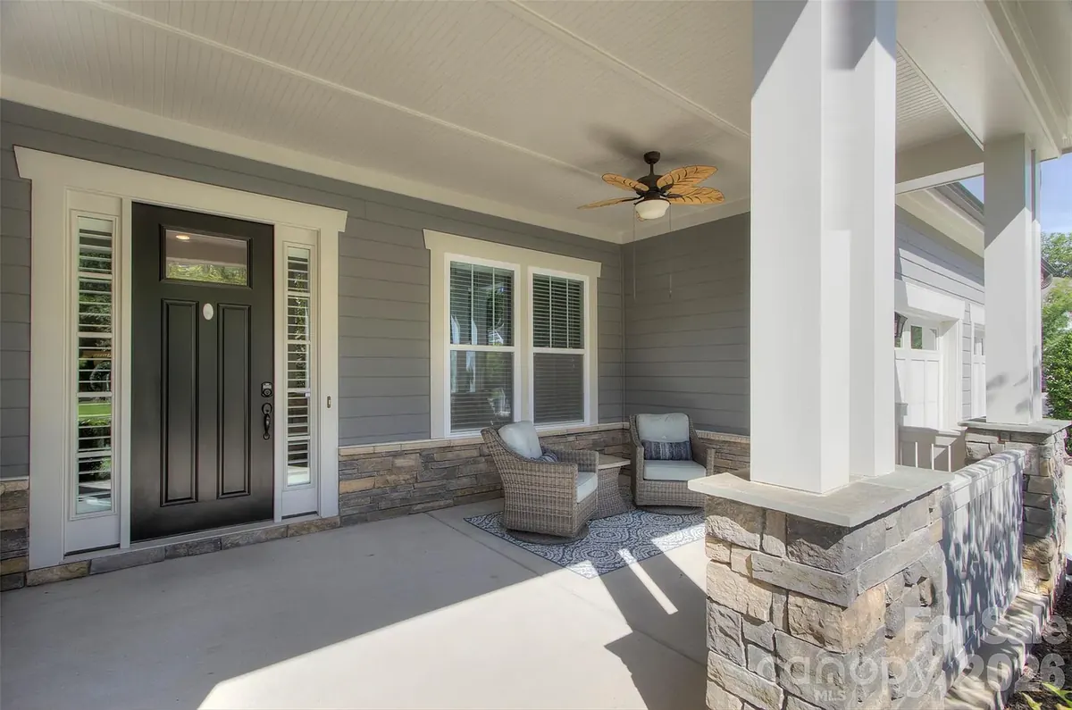 Covered front porch with stone accents and two wicker chairs