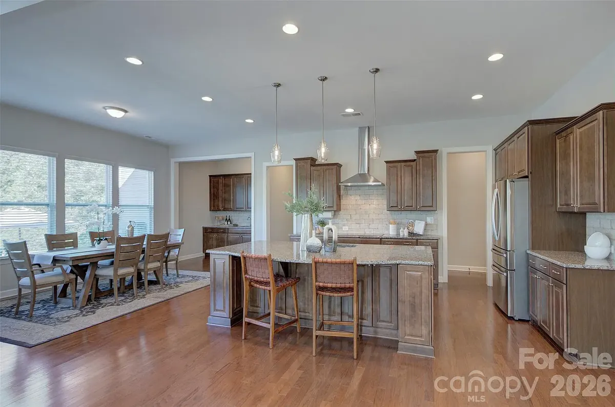 Open kitchen with a granite island and pendant lights, next to the dining area