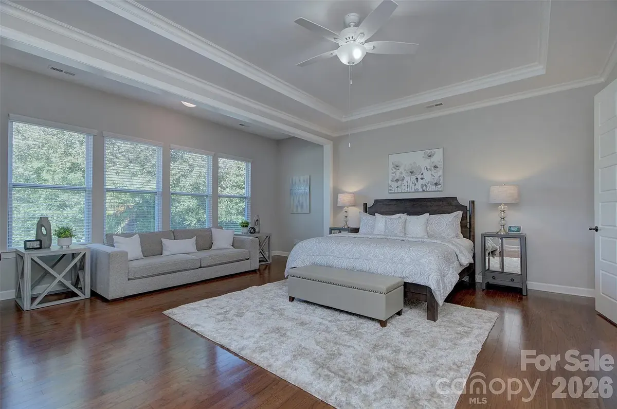 Primary bedroom with a tray ceiling and a sitting area by the windows